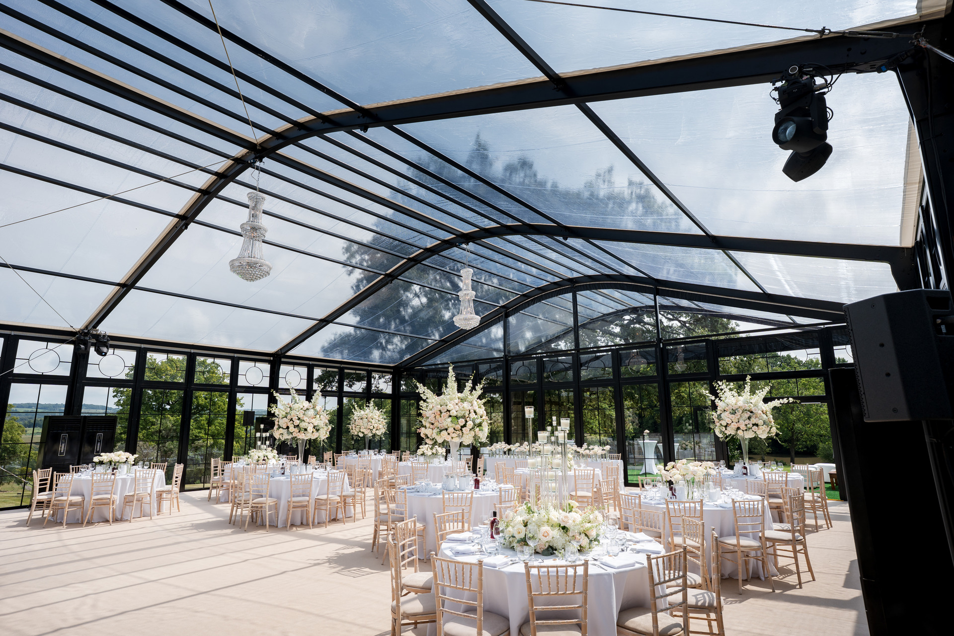 Dinner set in a glass-walled marquee with chandeliers