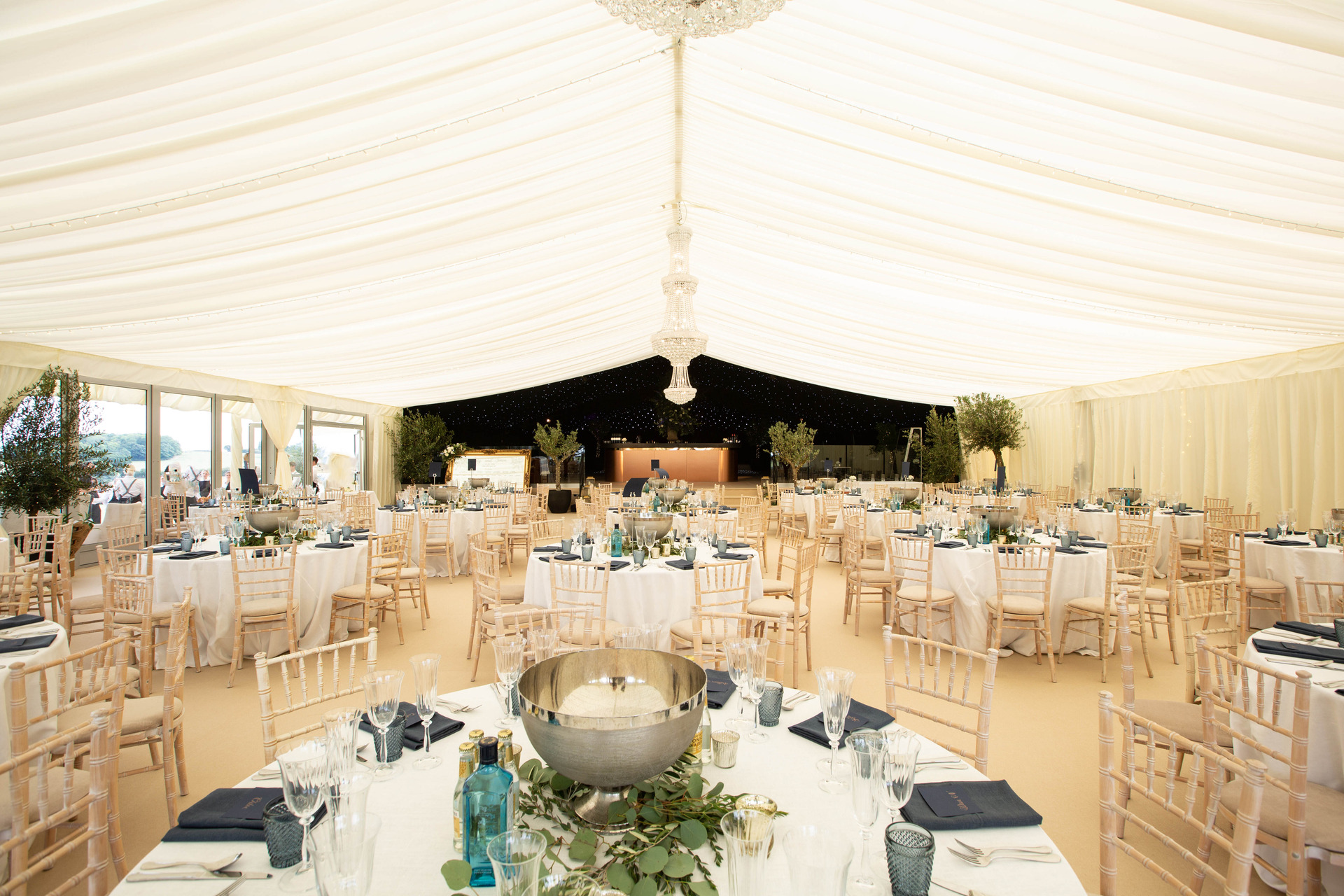 Dressed marquee interior with chandeliers and olive trees